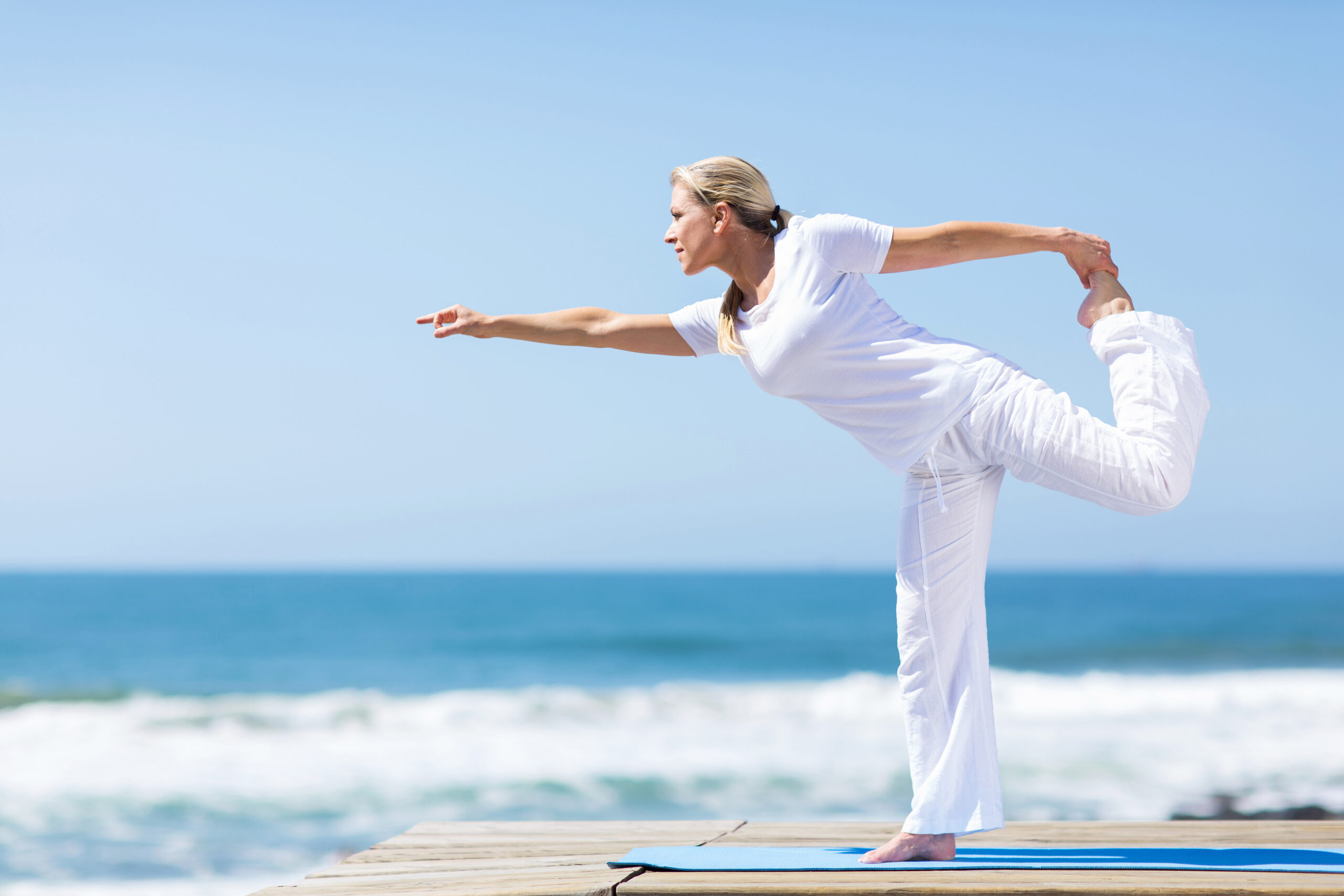middle aged woman doing yoga at the beach