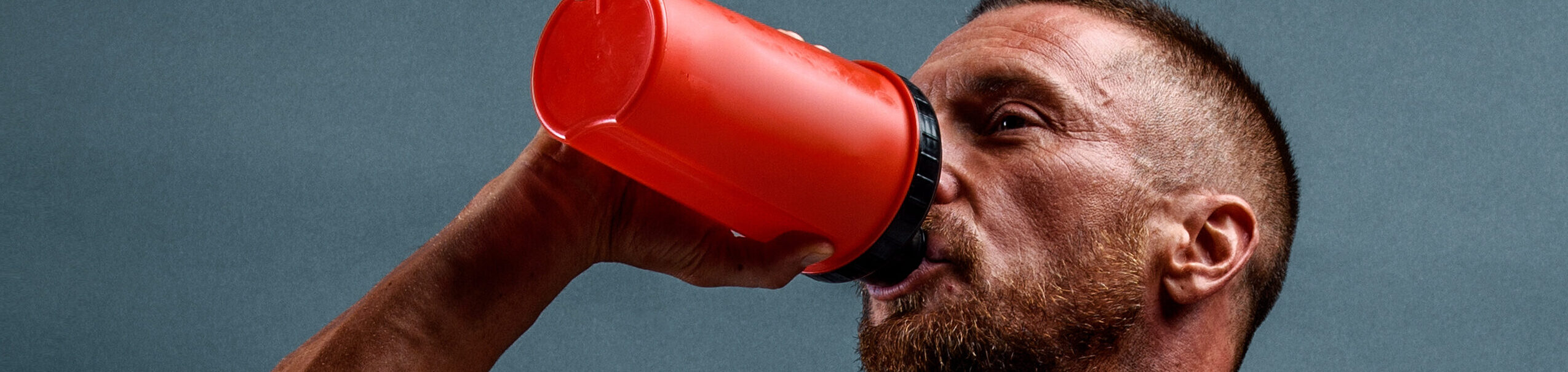 Muscular man drinks supplement after workout