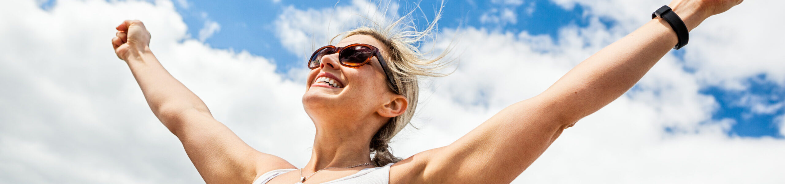 Carefree woman with arms outstretched against a blue sky