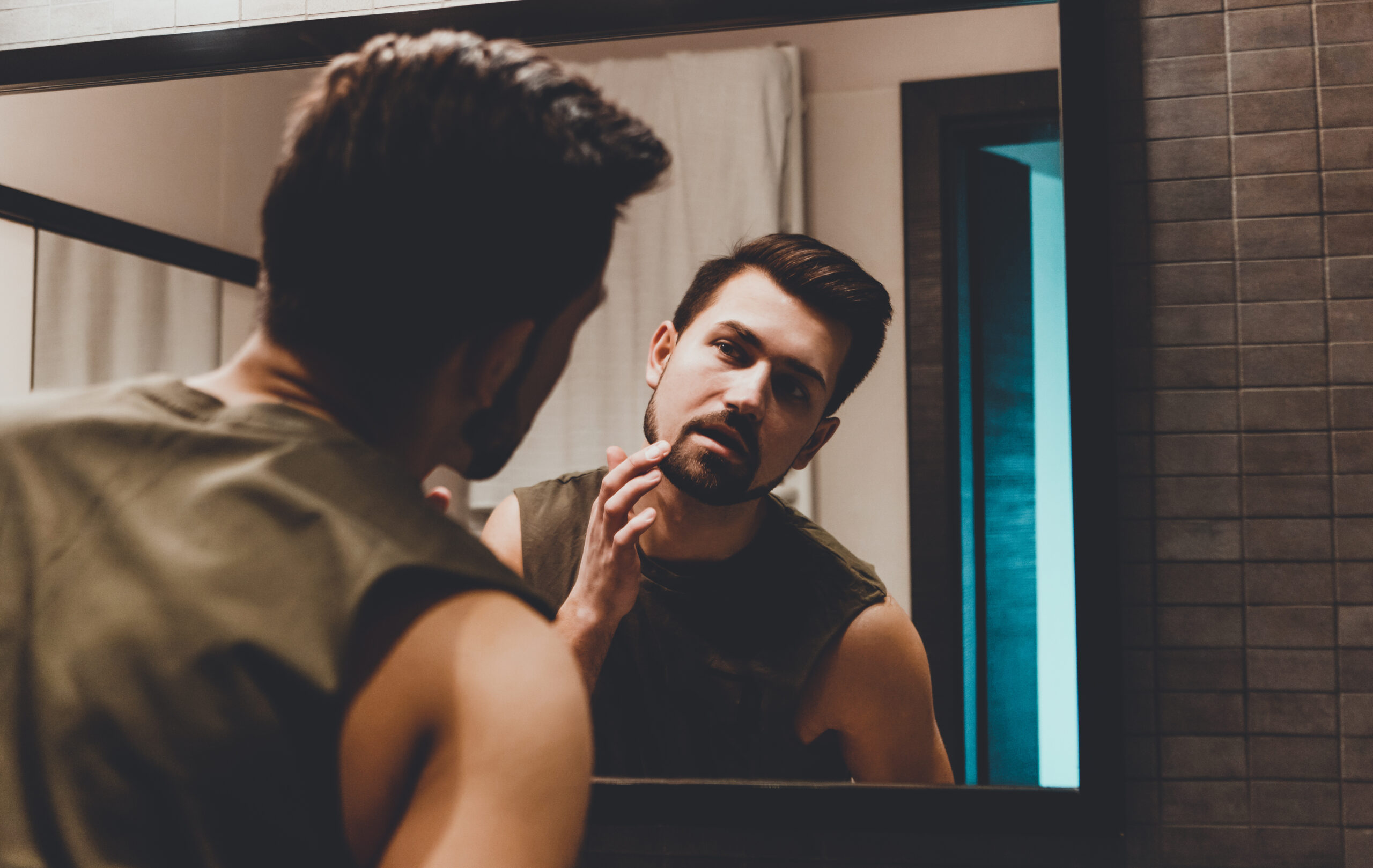 man looing in mirror wondering if he has Ozempic face.